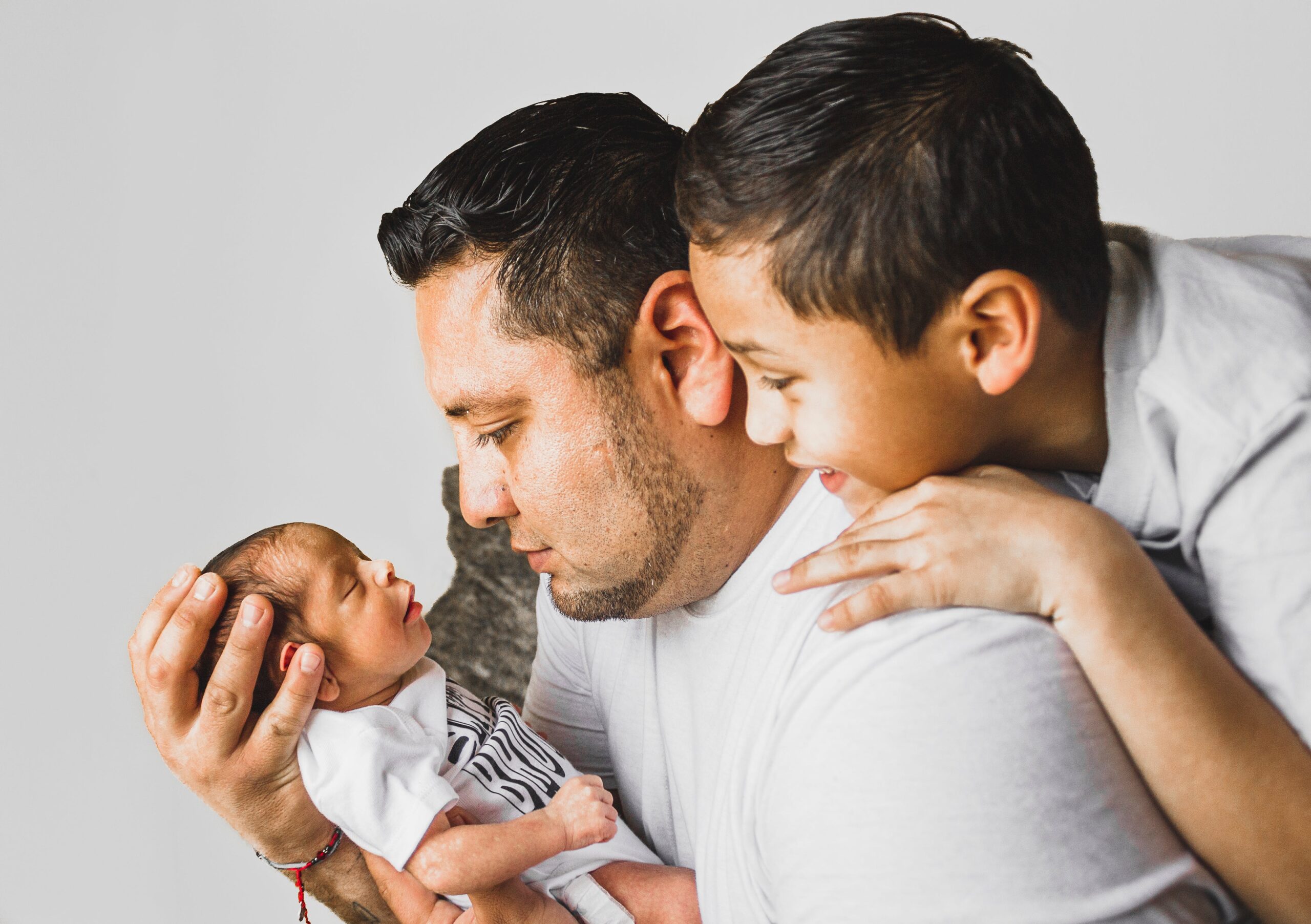 Father holding newborn and toddler